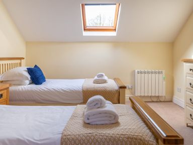 A bedroom with two single beds and folded towels under a skylight window at Bull Pen in Graythwaite near Hawkshead