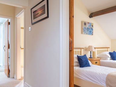 A hallway leading to a bedroom with two single beds and a wooden door at Bull Pen in Graythwaite near Hawkshead