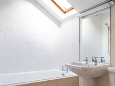 A bathroom with a bathtub sink and mirror under a skylight at Bull Pen in Graythwaite near Hawkshead
