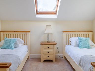 A bedroom with two single beds and a nightstand with a lamp under a skylight at Bull Pen Graythwaite near Hawkshead
