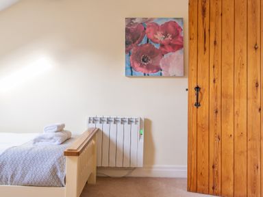 A bedroom with a bed with towels on it a radiator and a wooden door at Bull Pen Graythwaite near Hawkshead