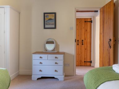 A bedroom with white wardrobe dresser with mirror and wooden doors at Bull Pen in Graythwaite near Hawkshead