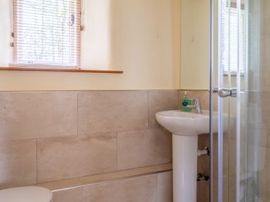 A bathroom with a window with blinds a pedestal sink with hand soap and a glass shower door at Bull Pen Graythwaite near Hawkshead