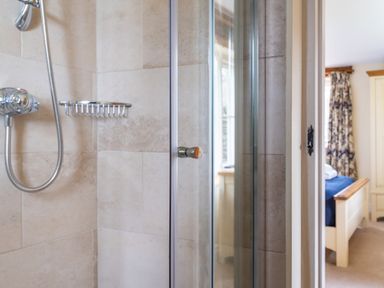 A shower area with a handheld showerhead and a metal soap holder next to a bedroom at Bull Pen in Graythwaite near Hawkshead