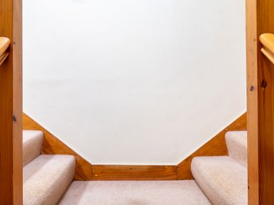 Carpeted stairs with wooden railings and white walls at Bull Pen in Graythwaite near Hawkshead