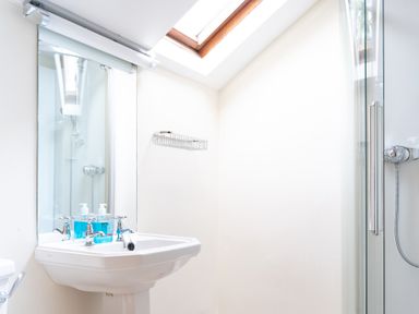 A bathroom with a sink mirror soap bottles a shower and a skylight at Bull Pen in Graythwaite near Hawkshead
