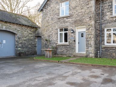 A stone cottage with blue doors and windows and a small patch of grass at Briar in Graythwaite near Hawkshead