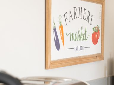 A kitchen wall with a framed farmers market sign above a countertop at Briar Graythwaite near Hawkshead