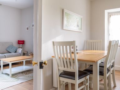 A dining area with a wooden table and four chairs next to a living room with a sofa and coffee table at Briar in Graythwaite near Hawkshead