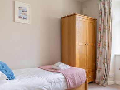 A bedroom with a single bed a wooden wardrobe floral curtains and a framed picture on the wall at Briar Graythwaite near Hawkshead