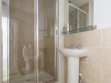 A bathroom with a glass shower enclosure a pedestal sink with two taps and a mirror with a glass shelf at Briar Graythwaite near Hawkshead