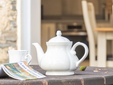 A white teapot and cup on a wooden table with a Lake District guidebook at Briar Graythwaite near Hawkshead