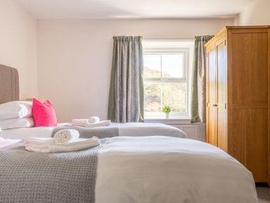 A bedroom with two single beds a wooden wardrobe and a window with curtains at Eel House Cottage Graythwaite Estate near Hawkshead