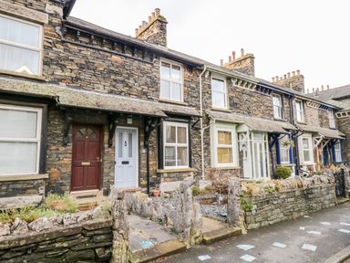 A row of stone terraced houses with different colored doors and small front gardens at Pottergill in Windermere