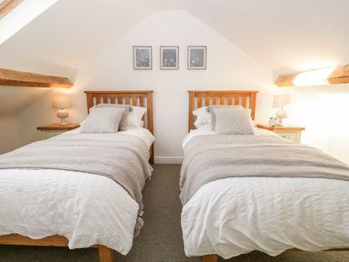 A bedroom with two single beds two lamps and three pictures on the wall at Pottergill in Windermere