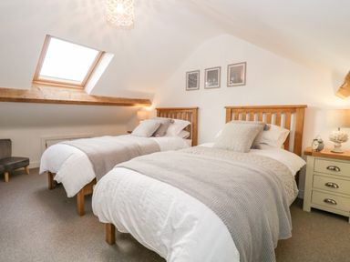 A bedroom with two single beds a skylight window and a bedside table at Pottergill in Windermere
