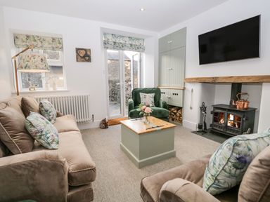 A living room with two sofas a green armchair a wooden chest a fireplace and a wall-mounted TV at Pottergill in Windermere