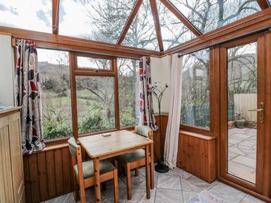 A conservatory with a table and chairs at Calcott Annexe in Whitchurch, Herefordshire