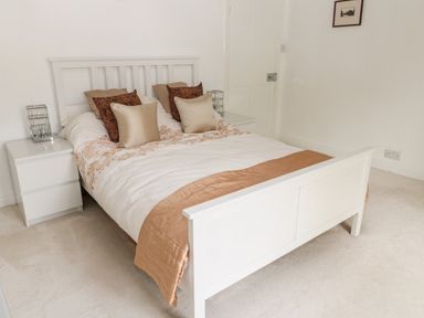 A bedroom with a white bed frame pillows and matching nightstands at 1A Chantry Place in Morpeth