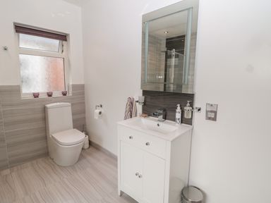 A bathroom with a toilet a sink with a cabinet and a mirror at 1A Chantry Place Morpeth