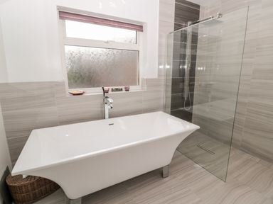 A bathroom with a white freestanding bathtub and a glass shower enclosure at 1A Chantry Place in Morpeth