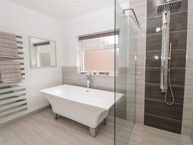 A bathroom with a freestanding bathtub a glass shower enclosure and a towel rack at 1A Chantry Place in Morpeth