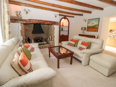 A living room with two white sofas a wooden coffee table and a stone fireplace at 1A Chantry Place in Morpeth