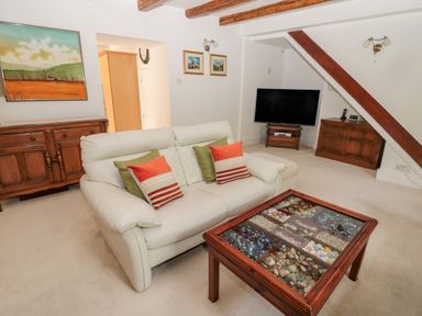 A sitting room with a white sofa and a glass top coffee table displaying stones and shells at 1A Chantry Place in Morpeth