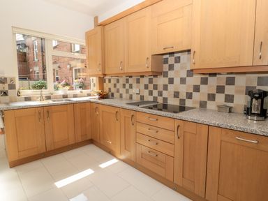 A kitchen with wooden cabinets a granite countertop a coffee maker and a window showing an outside view at 1A Chantry Place in Morpeth