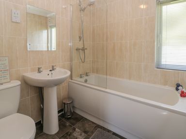 A bathroom with a bathtub shower sink toilet and window blinds at Jonstone Pines in Cayton Bay near Scarborough
