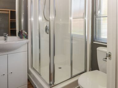 A bathroom with a shower cabin toilet sink and a window with blinds at Jonstone Pines in Cayton Bay near Scarborough