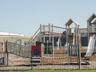 A wooden playground with slides bridges and climbing structures surrounded by a metal fence at Jonstone Pines in Cayton Bay near Scarborough