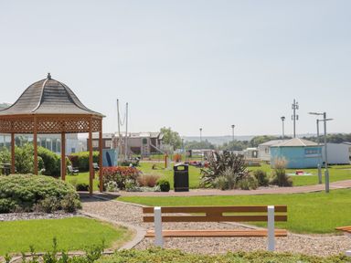 A park area with benches a pavilion and a playground near caravans at Jonstone Pines in Cayton Bay near Scarborough