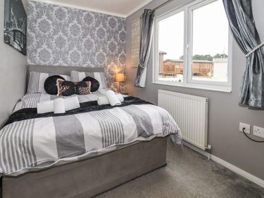 A bedroom with a double bed pillows bedside lamp window and radiator at Jonstone Pines in Cayton Bay near Scarborough