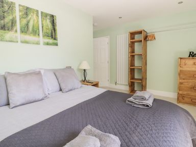 A bedroom with a bed with pillows and folded towels a wooden shelving unit and a wooden dresser at Bluebell Wood in Brandesburton