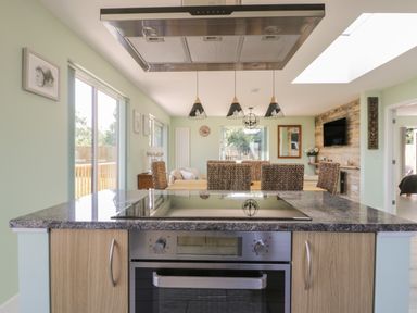 A kitchen island with oven and cooktop in an open plan dining and living area at Bluebell Wood in Brandesburton