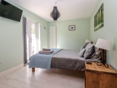 A bedroom with a bed and a TV at Bluebell Wood in Brandesburton