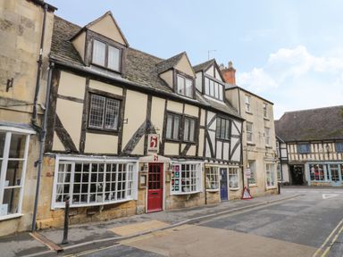 A street view of historic half timbered buildings with windows and doors at Thimble Cottage in Winchcombe