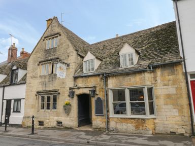 A stone building with a sign reading the lion inn and windows along a street at Thimble Cottage in Winchcombe