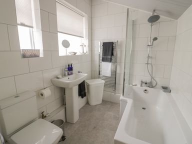 A bathroom with a toilet sink bathtub and towel rack at Thimble Cottage in Winchcombe