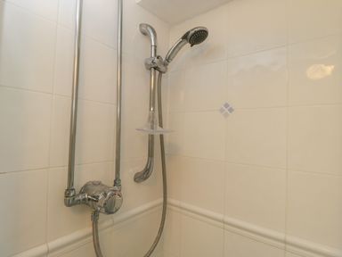 A shower head and control valve on tiled bathroom wall at Athelstan Cottage Chloe Mead near Stroud