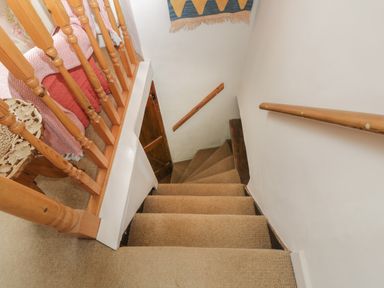 A narrow carpeted staircase with wooden handrails and a wooden banister at Athelstan Cottage in Chloe Mead near Stroud
