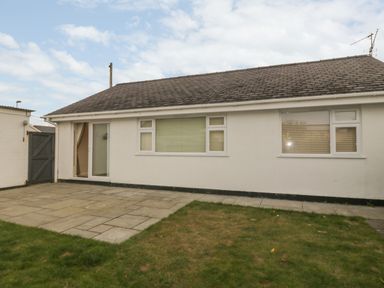 A single story house with a tiled roof patio and grass lawn at Glanaig in Morfa Bychan