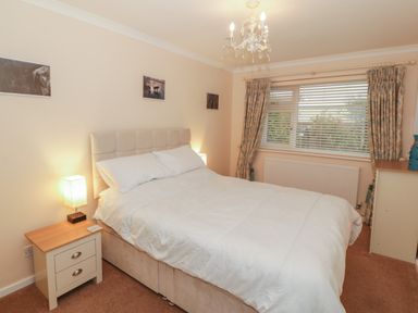 A bedroom with a double bed bedside tables lamps window with blinds and curtains at Glanaig Morfa Bychan