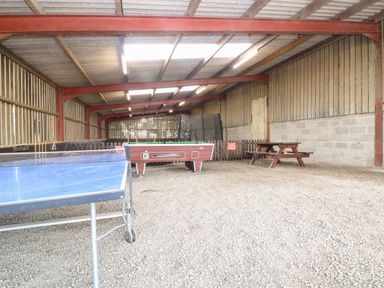 A covered recreational area with a ping pong table a foosball table and a picnic bench at Norton Cottage in Craven Arms