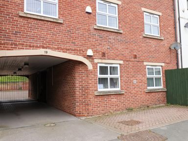 A red brick building with multiple white windows a gated archway and a green fence at Cadliam Whitby