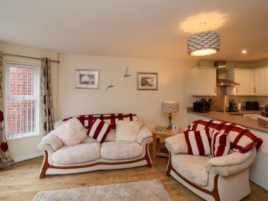 A living room with two sofas a side table with lamp and an open kitchen at Cadliam in Whitby