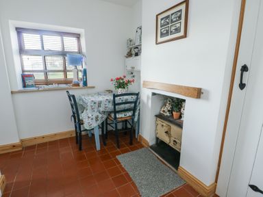 A dining area with a table and chairs next to a window and a fireplace at Old Tollgate in Gwalchmai near Llangefni