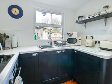 A kitchen with a sink microwave kettle toaster and shelves with jars at Old Tollgate in Gwalchmai near Llangefni