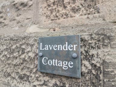 A sign reading Lavender Cottage mounted on a stone wall at Lavender Cottage in Glanton
